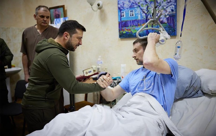 n this photo provided by the Ukrainian Presidential Press Office on Sunday, March 13, 2022, President Volodymyr Zelenskyy, center, shakes hands with a wounded soldier during his visit to a hospital in Kyiv, Ukraine.
