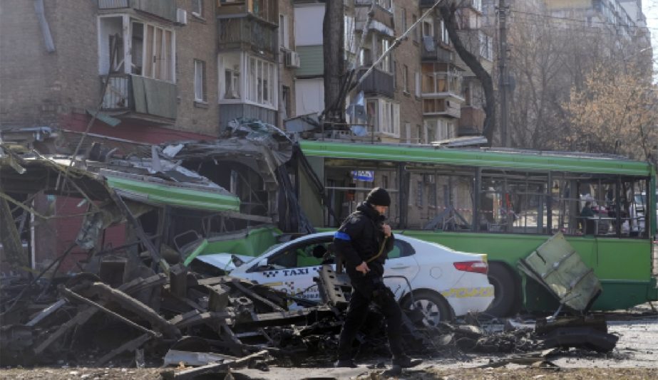 A Ukrainian soldier passes by a destroyed a trolleybus and taxi after a Russian bombing attack in Kyiv, Ukraine, Monday, March 14, 2022.