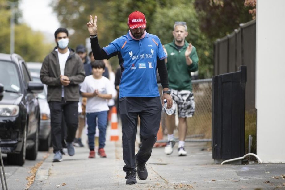Al Noor Mosque shooting survivor Temel Atacocugu gestures as he completes his walk from Dunedin to Christchurch on the third anniversary of the shootings in Christchurch, New Zealand, Tuesday, March 15, 2022.