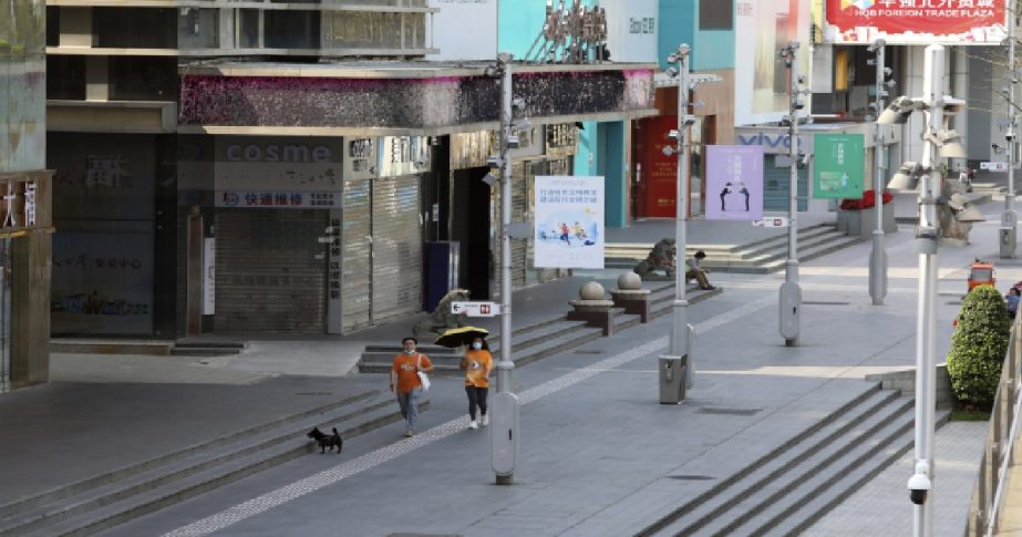 Residents walk their dog past shuttered shops in the Huaqiangbei area, the world's biggest electronics market, in Shenzhen, southern China's Guangdong province Monday, March 14, 2022.