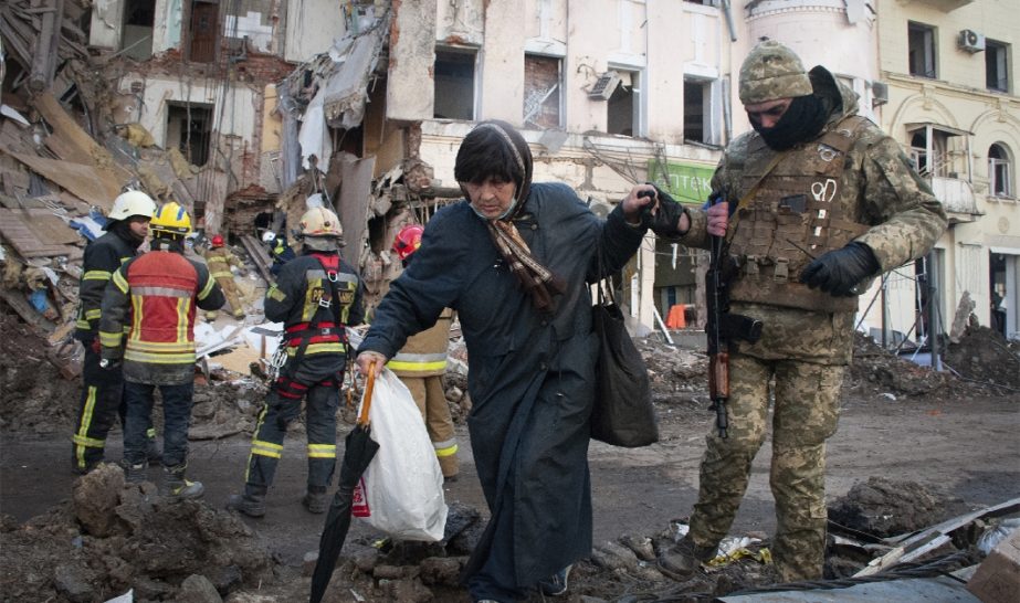 A volunteer of the Ukrainian Territorial Defense Forces assists a woman to cross the street in Kharkiv, Ukraine, Wednesday, March 16, 2022.