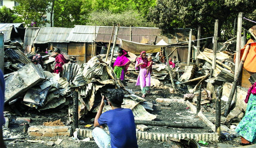 Ill-fated slum-dwellers are seen amid the slew of charred belongs on Monday as a fire that broke out at Kalyanpur adjacent to Beltolamath slum on Sunday.