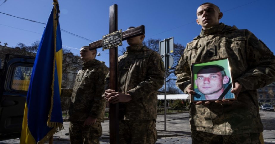 A Ukrainian soldier holds the photograph of 47-year-old soldier Roman Valkov, during his funeral ceremony, after being killed in action, at the Holy Apostles Peter and Paul Church in Lviv, western Ukraine, Monday, March 28, 2022.