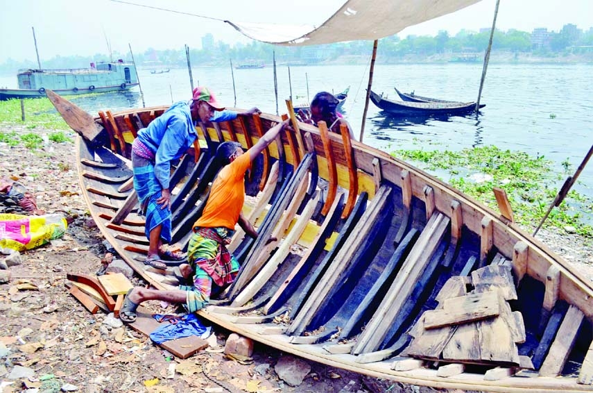 Boatmen are seen busy with repairing boats ahead of the rainy season. This photo was taken from Kamrangirchar area in the capital on Thursday.
