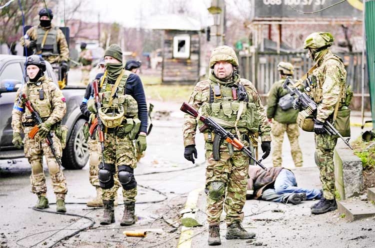 Ukrainian servicemen stand next to the body of a man in civilian clothing on the outskirts of the Ukrainian capital yesterday. Agency photo