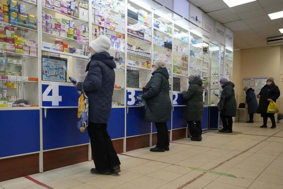 Customers stand at the windows buying medicines in a pharmacy in St. Petersburg, Russia, Friday, April 1, 2022.