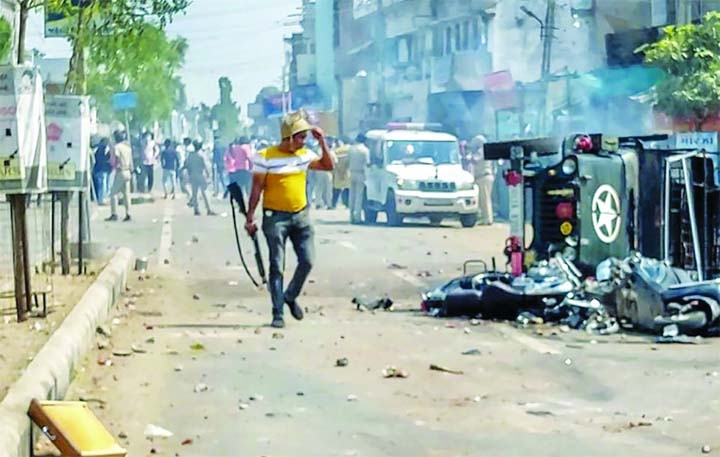 A policeman near a burnt vehicle as police try to control the situation after a communal clash during the Ram Navami procession, in Himmatnagar, Gujarat on Sunday.