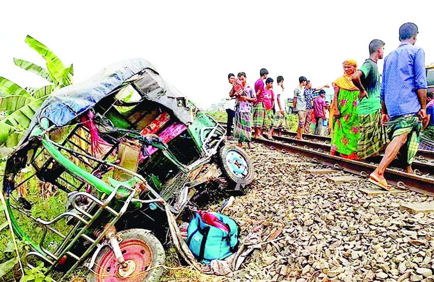 Onlookers stand in front of a mangled CNG-run autorickshaw beside rail line as a train rammed down the autorickshaw in the eastern side of Bangabandhu Bridge in Tangail on Monday leaving 3 people dead.