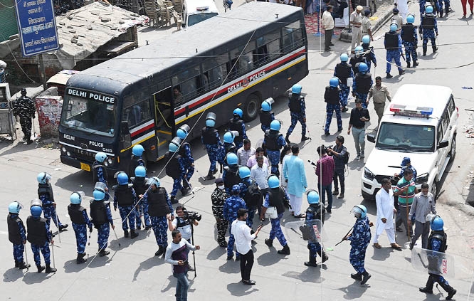 Rapid Action Force (RAF) personnel deployed to secure a residential area walk along a street in Jahangirpuri area in New Delhi, India on Sunday.