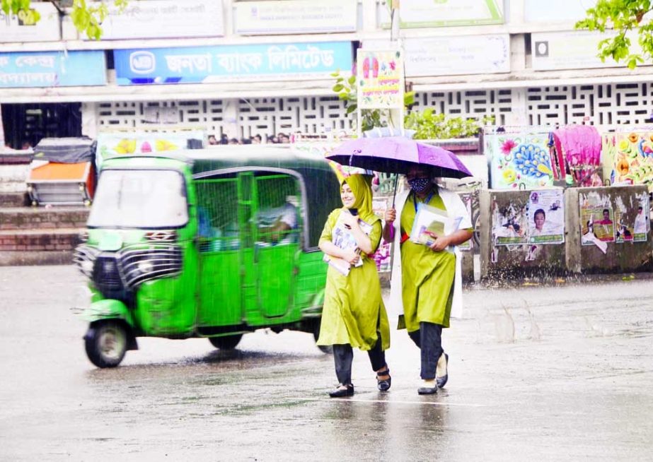 Two college girls walk in rain under an umbrella in a street following the nor’wester that lashed in the capital early Wednesday. NN photo