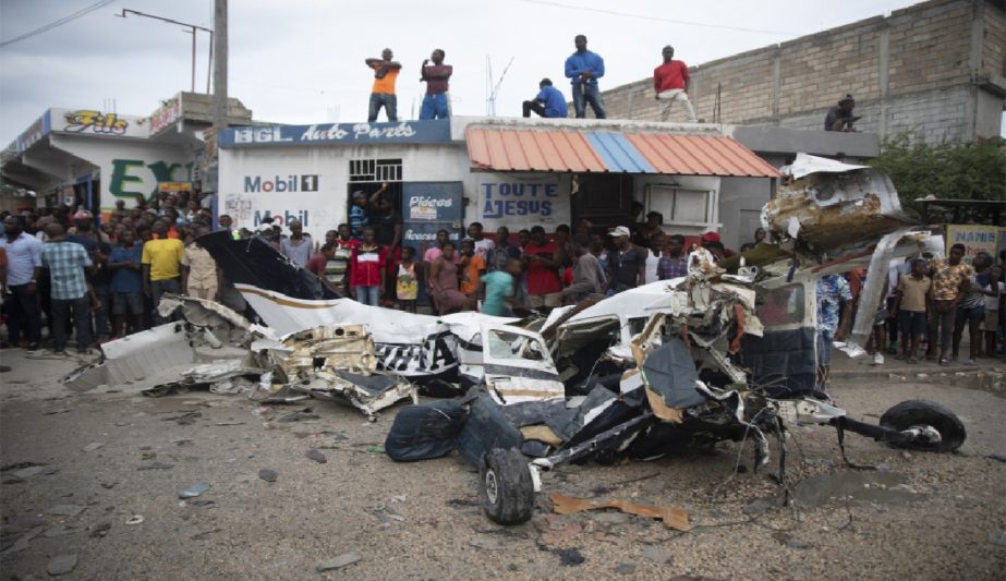 Onlookers mill around the wreckage of a small plane that crashed in the community of Carrefour, Port-au-Prince, Haiti, Wednesday, April 20, 2022.