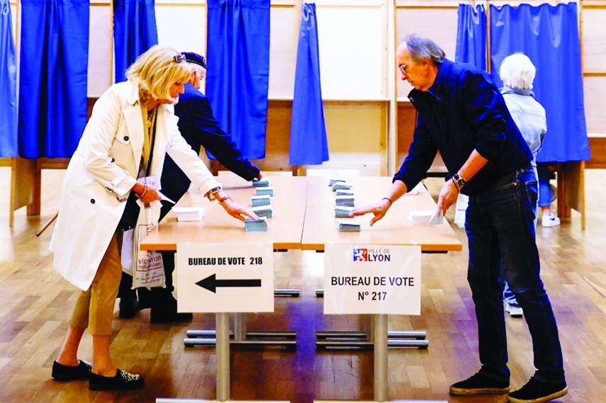 Voters take ballots from stacks displayed on tables in the second round of the 2022 French presidential election at a polling station in Lyon, France on Sunday.
