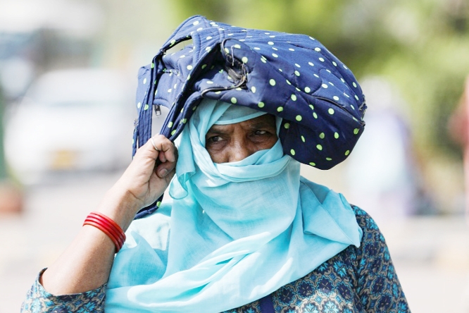 Woman uses her bag to protect herself from the sun on a hot summer day in New Delhi.