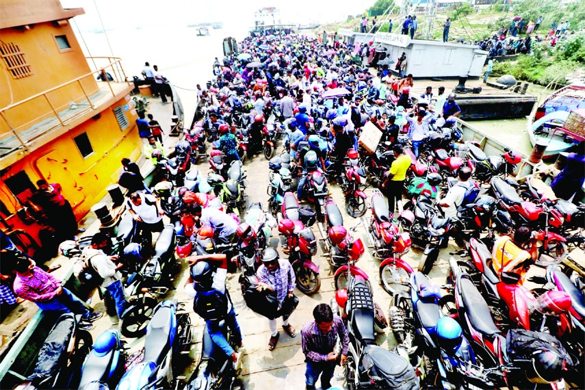 A huge number of home-bound people along with their motorcycles take ride on a ferry to cross the river Padma through the Shimulia-Banglabazar route on Saturday ahead of Eid-ul-Fitr.