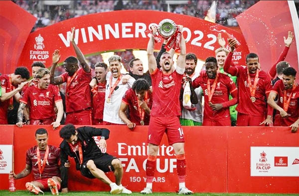 Liverpool's midfielder Jordan Henderson (center) holds the trophy as he celebrates with teammates after winning the English FA Cup final football match against Chelsea at Wembley stadium in London on Saturday.