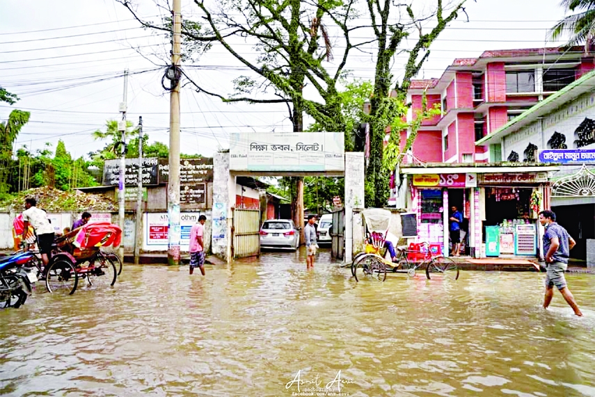 People wade through floodwater in Sylhet city on Wednesday as several roads went underwater due to incessant rains for the past few days.