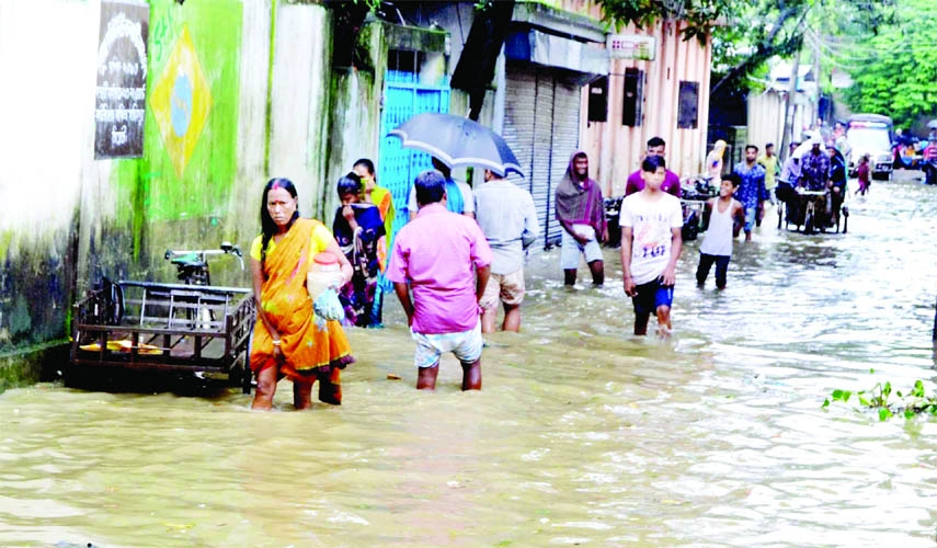 Locals wade through waterlogged road created by flood water due to onrush of hill water coming from Indian upstream. This photo was taken from Sunamganj suburb area on Sunday.