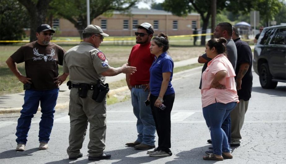 A policeman talks to people asking for information outside of the Robb Elementary School in Uvalde, Texas, Tuesday, May 24, 2022.