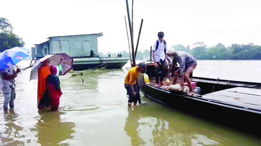 Due to worsening of flood situation in Sunamganj local people wading through the water to board on a boat as the ferry remained out of operation. This photo was taken from the RP Nagar lunch ghat of Sunamganj Municipality on Wednesday.