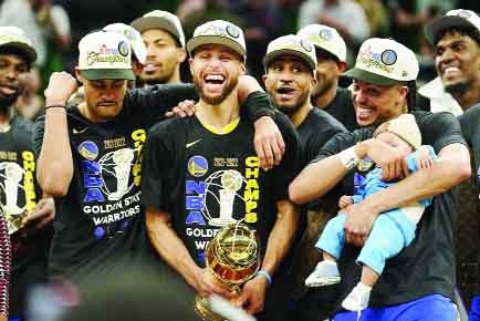 Golden State Warriors guard Stephen Curry (center) celebrates with teammates as he holds the Bill Russell Trophy for Most Valuable Player after the Warriors beat the Boston Celtics in Game 6 to win basketball's NBA Finals in Boston on Thursday.