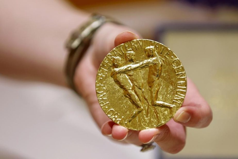 A worker holds Russian journalist Dmitry Muratov's 23-karat gold medal of the 2021 Nobel Peace Prize before being auctioned at the Times Center, Monday, June 20, 2022, in New York.