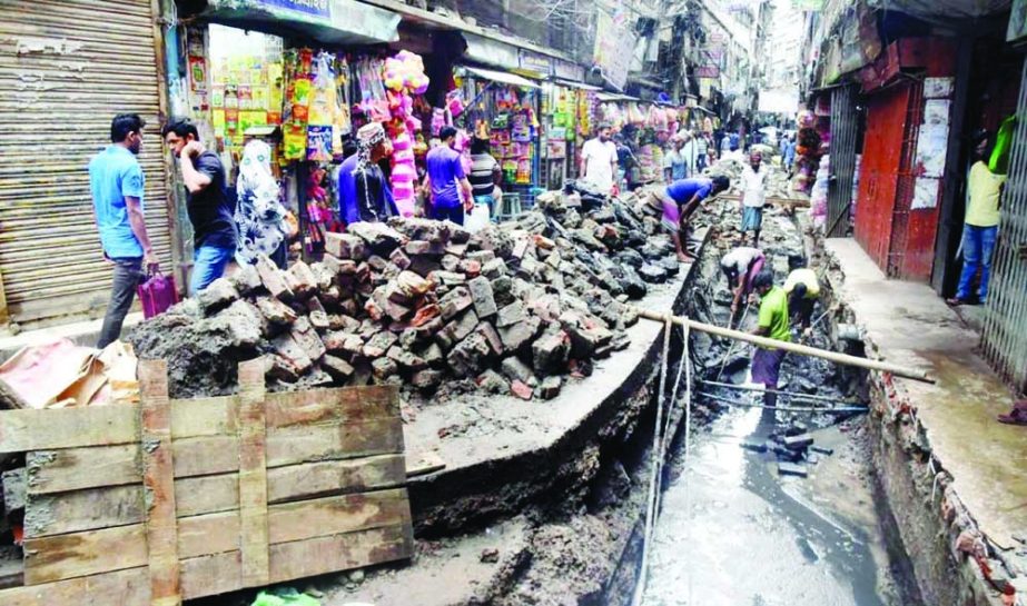 Pedestrians move through dilapidated road on the entrance of Moulvibazar in the capital on Tuesday due to construction of drainage system. As a result, the plight to wayfarers knew no bounds. NN photo