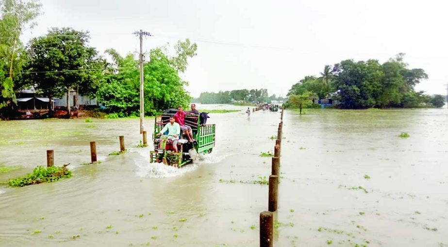 A vehicle wades through flood water flowing over the Melandah-Mahmudpur road in Jamalpur on Wednesday. The district hit by flood due to continuous rising of water level in the River Jamuna. NN photo