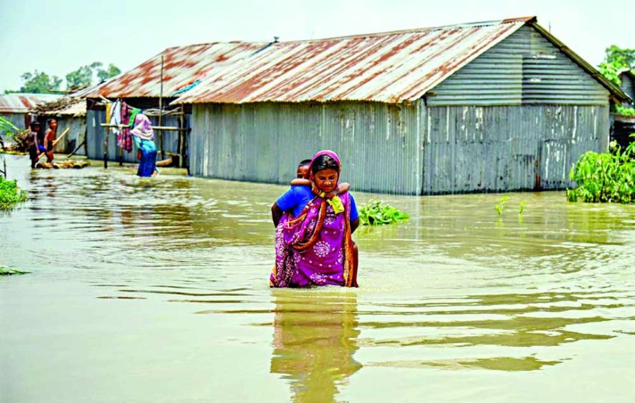 A woman carries her child on the back as she wades through floodwaters at Kamarjani village in Gaibandha district on Thursday. NN photo