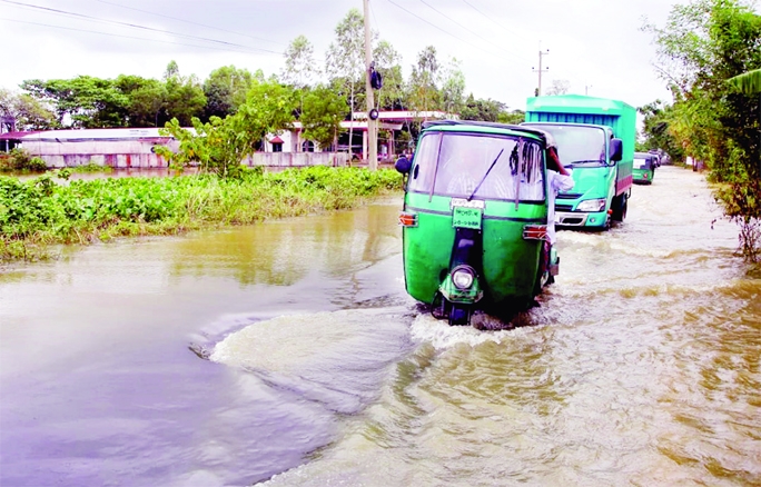 Vehicles move through a waterlogged road on Sylhet-Fenchuganj Highway on Wednesday because floodwater inundated villages as Kushiyara River water was flowing above danger mark.