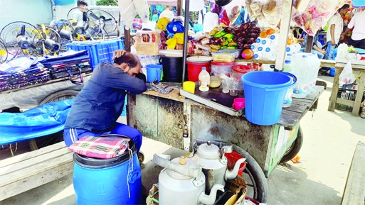 A tea seller spends time by sleeping at his stall on the pavement in front of Dhaka Medical College on Wednesday as the number of customers was scanty due to upsurge of Covid cases in recent days.