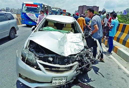 Onlookers stand in front of a maimed private car after being collided with a motorcycle on the flyover in Konabari of Gazipur district of Friday triggering 3 people dead.