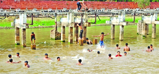 Children are seen frolicking in dirty water in order to get relief from scorching heat of summer. This photo was taken from in the capital on Friday.