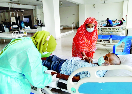 A medical staff feels the pulse of a patient at Mohakhali DNCC Covid Hospital in the capital on Sunday, as number of Corona patients rising across the country everyday.
