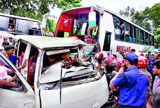 Onlookers stand in front of a smashed microbus after it collided head-on with a bus at New Shikarpur under Wazirpur upazila on Dhaka-Barishal Highway on Thursday leaving five microbus passengers dead and eight others injured.