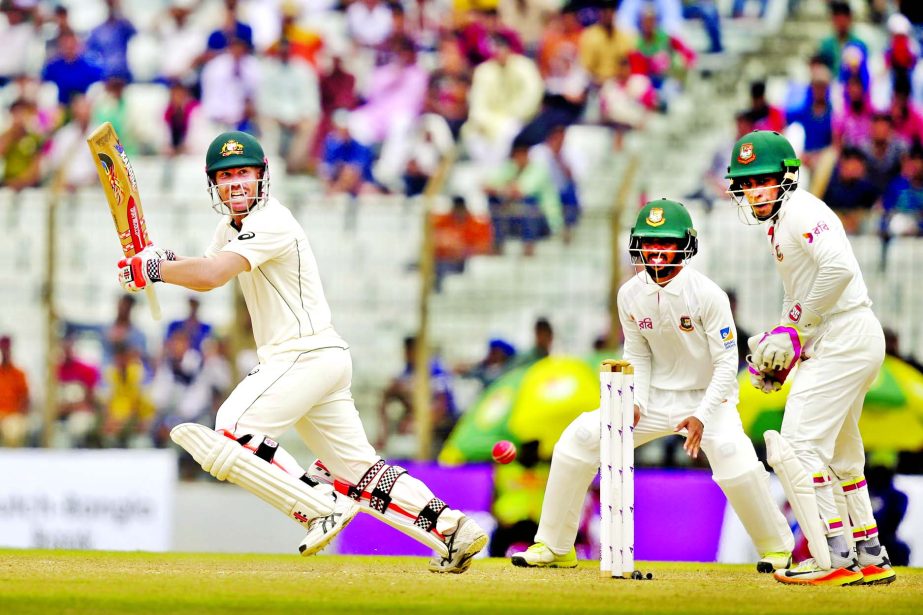 Australia's David Warner (left) plays a shot as Bangladesh's wicketkeeper captain Mushfiqur Rahim (right) and his teammate Mominul Haque watch the ball on the 2nd day of the 2nd Test match between Bangladesh and Australia at Zahur Ahmed Chowdhury Stadiu