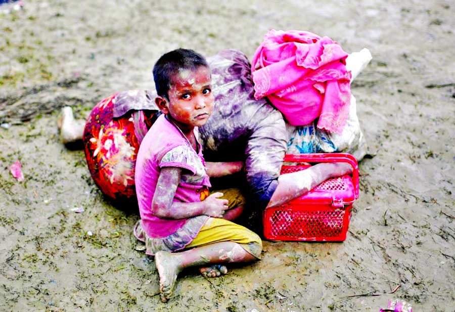 A Rohingya refugee girl sits next to her mother who rests after crossing the Bangladesh-Myanmar border in Teknaf, Bangladesh on Wednesday.