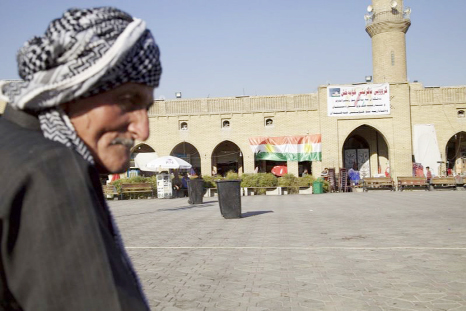 An elderly man sits in the center of Irbil near a campaign poster urging people to vote yes in the upcoming poll on independence from Iraq.