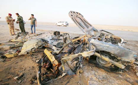 Iraqi security forces inspect the site of a bomb attack at a police checkpoint on a highway near the southern Iraqi city of Nassiriya on Thursday.