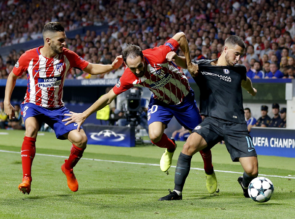 Atletico's Koke (left) looks on as Atletico's Juanfran (center) and Chelsea's Eden Hazard (right) challenge for the ball during a Champions League group C soccer match between Atletico Madrid and Chelsea at the Wanda Metropolitan stadium in Madrid, Spa