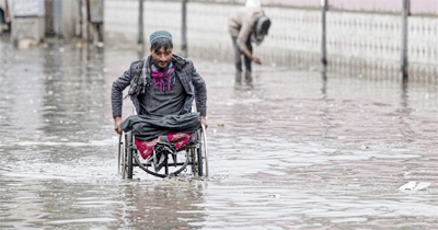 File photo: A man on a wheelchair makes his way through flood waters after heavy rains in Kabul, Afghanistan.