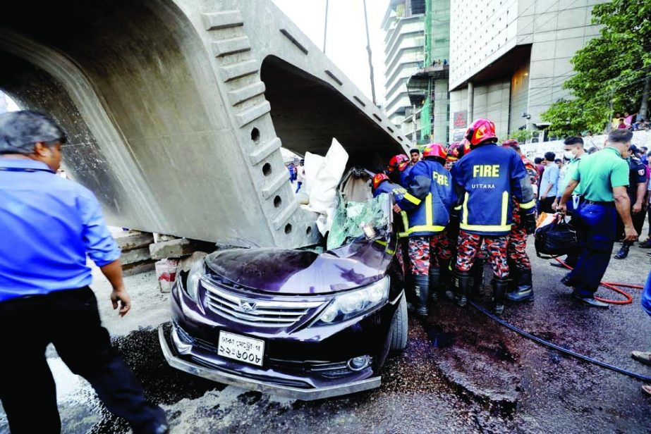 A girder of the under construction Bus Rapid Transit (BRT) project falls on a car at Uttara in the capital on Monday when it was moved by a crane. NN photo