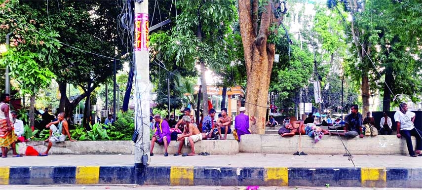 People taking rest under a tree after taking off their shirt due to extreme heat in the city's Motijheel area on Thursday. NN photo