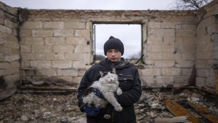 Danyk Rak, 12, holds a cat standing on the debris of his house destroyed by Russian forces' shelling in the village of Novoselivka, near Chernihiv, Ukraine, April 13, 2022. File photo