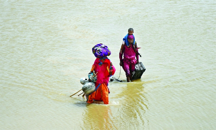 A family with their belongings wade through rain waters following rains and floods during the monsoon season in Jamshoro, Pakistan on Friday.