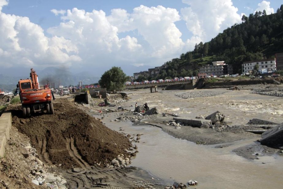Local authorities use heavy machinery to rebuild a damaged road after a flood-affected area, in Swat valley, Pakistan, Sunday, Aug. 28, 2022.