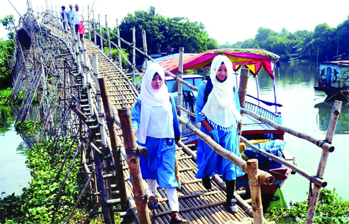 People crossing a canal by using a bamboo bridge at Nandipara of Khilgaon in the capital on Friday.