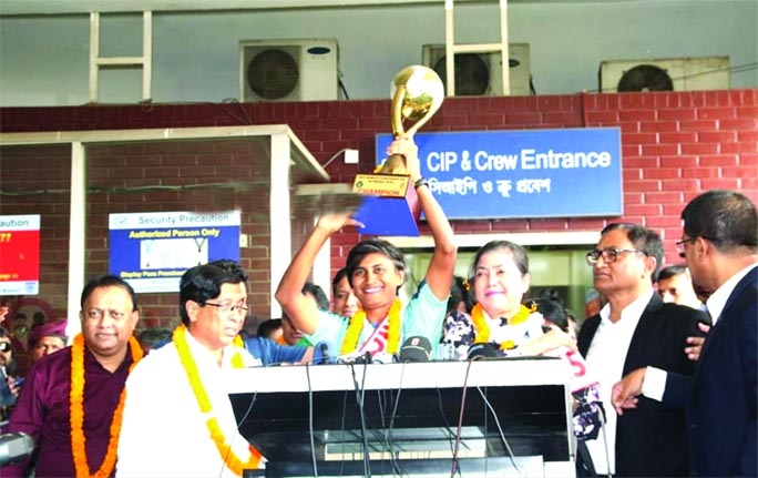 Captain of Bangladesh Women's Football team Sabina Khatun raises the championship trophy of the SAFF Women's Championship at the Hazrat Shahjalal International Airport in Dhaka on Wednesday.