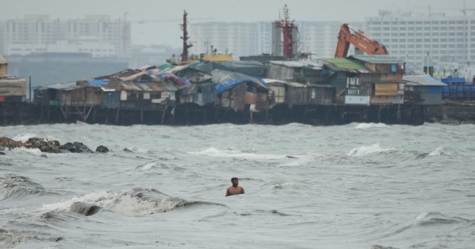 A resident swims along strong waves as Typhoon Noru approaches the seaside slum district of Tondo in Manila, Philippines, Sunday, Sept. 25, 2022.