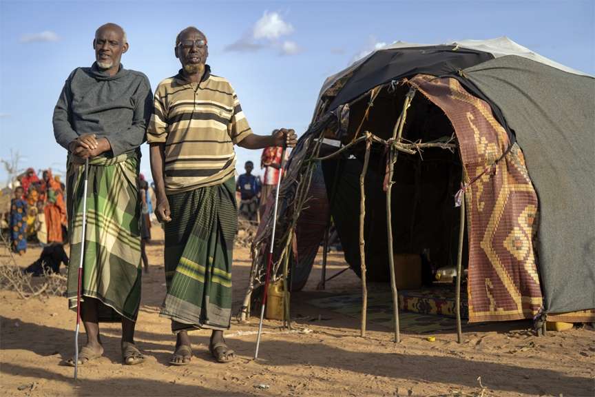 Mohamed Kheir Issack, 80, right, and and Issack Farow Hassan, 75, stand outside Issack's shelter at a camp for displaced people on the outskirts of Dollow, Somalia on Tuesday, Sept. 20, 2022.